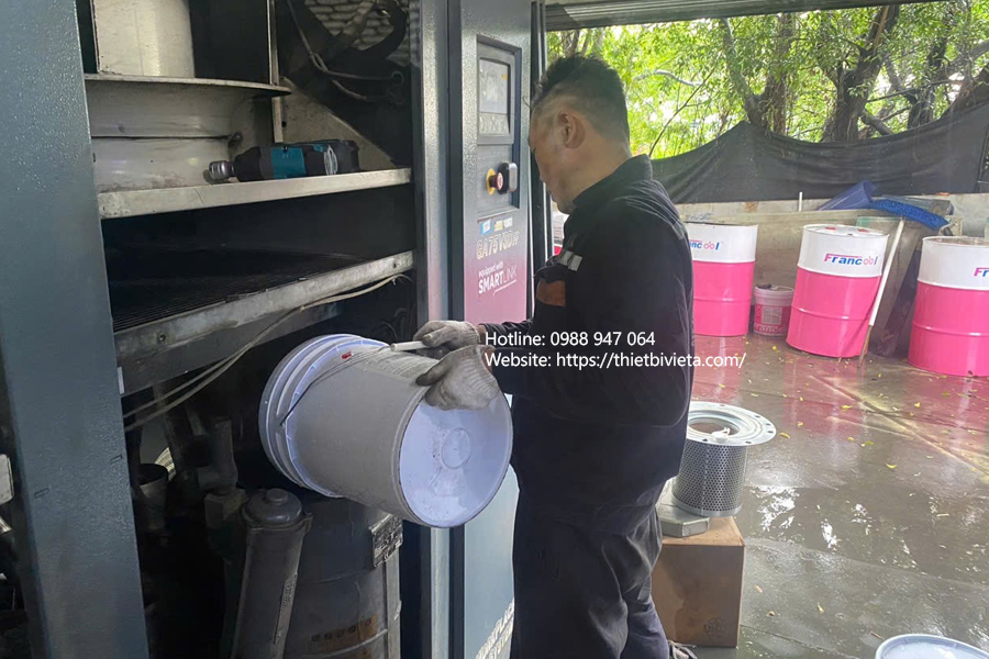 kỹ thuật viên đổ dầu mới cho máy nén khí